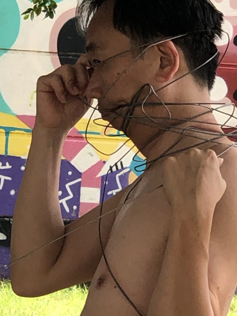Philemon Mukarno perform naked involves him entangling his body with thick iron wires, which feel oppressive and heavy, and every movement causes pain due to the iron wires.