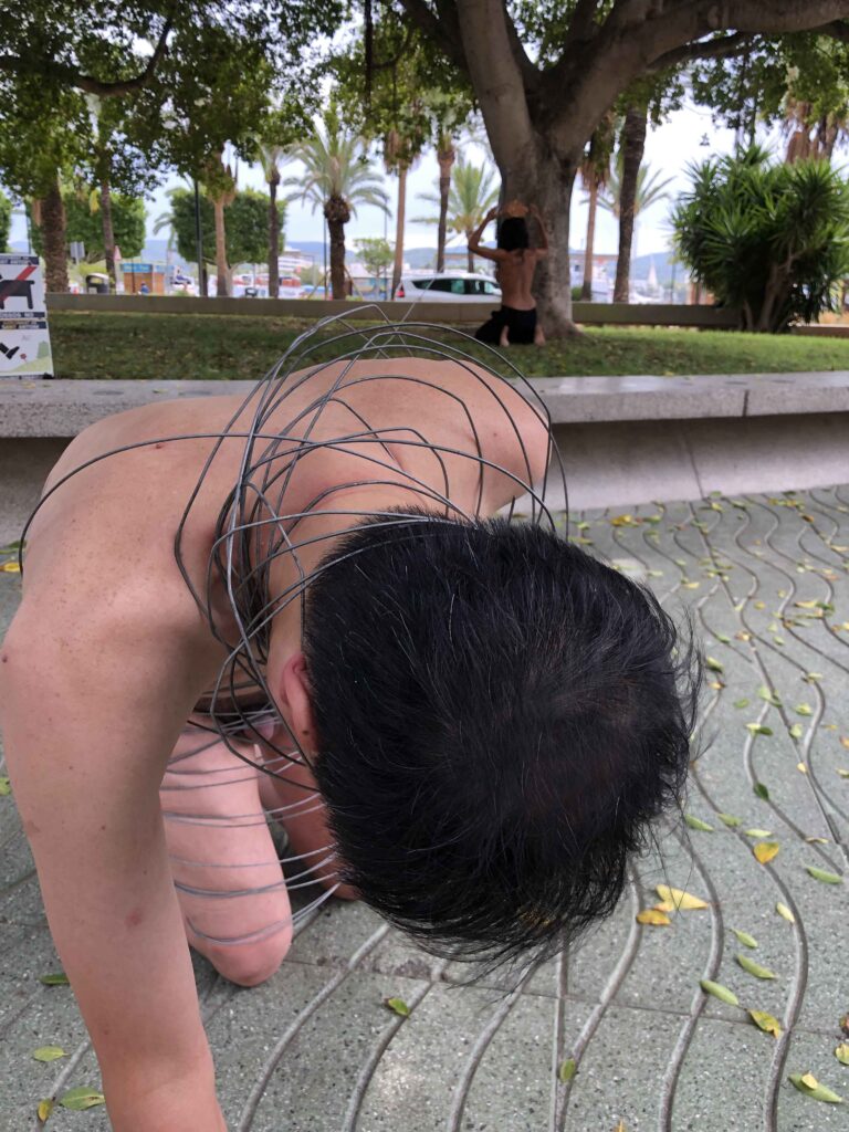 Philemon Mukarno perform naked involves him entangling his body with thick iron wires, which feel oppressive and heavy, and every movement causes pain due to the iron wires.