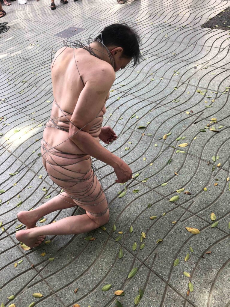 Philemon Mukarno perform naked involves him entangling his body with thick iron wires, which feel oppressive and heavy, and every movement causes pain due to the iron wires.