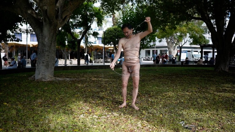 Philemon Mukarno perform naked involves him entangling his body with thick iron wires, which feel oppressive and heavy, and every movement causes pain due to the iron wires.