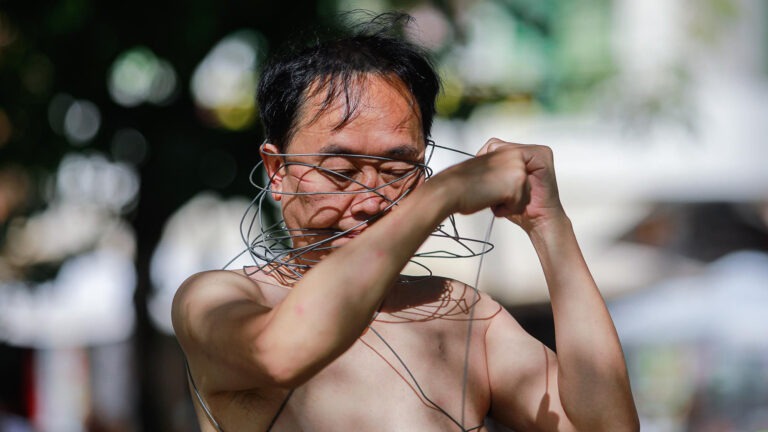 Philemon Mukarno perform naked involves him entangling his body with thick iron wires, which feel oppressive and heavy, and every movement causes pain due to the iron wires.