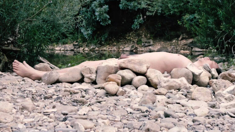 Philemon Mukarno lying naked on stones