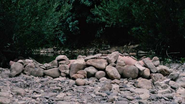 Philemon Mukarno lying naked on stones