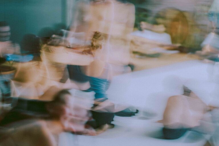 Een groep mensen die zich bezig houden met lichaamswerk of groepsinteractie, met een mix van naakte en geklede individuen die elkaar steun bieden en hun gevoelens delen in een sombere omgeving.