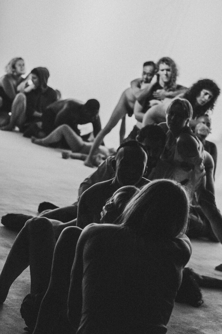 Group of naked people sitting and lying in an artistic composition on the ground in black and white