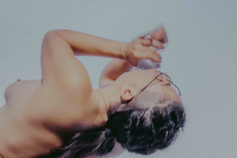 Een groep mensen die zich bezig houden met lichaamswerk of groepsinteractie, met een mix van naakte en geklede individuen die elkaar steun bieden en hun gevoelens delen in een sombere omgeving.