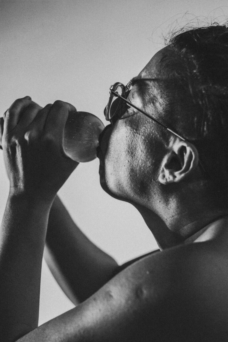 Person in profile drinking from a bottle in black and white