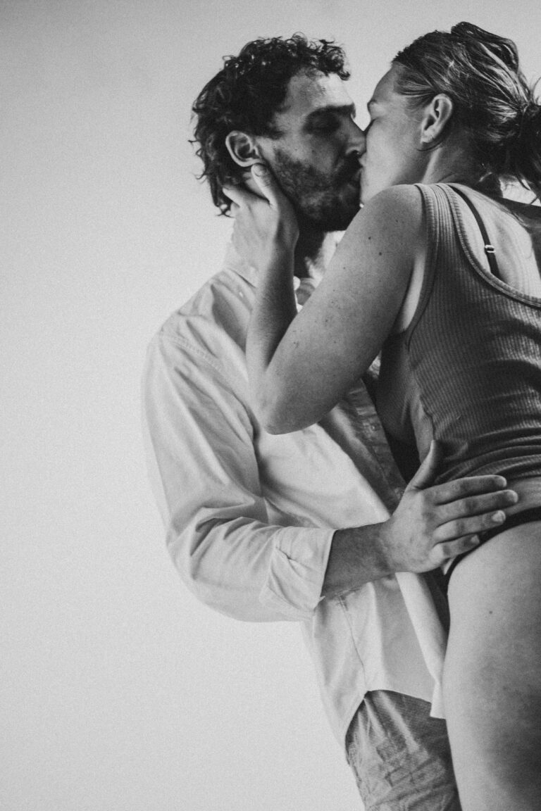 Man and woman kissing intimately, with the man in white shirt and woman in tank top