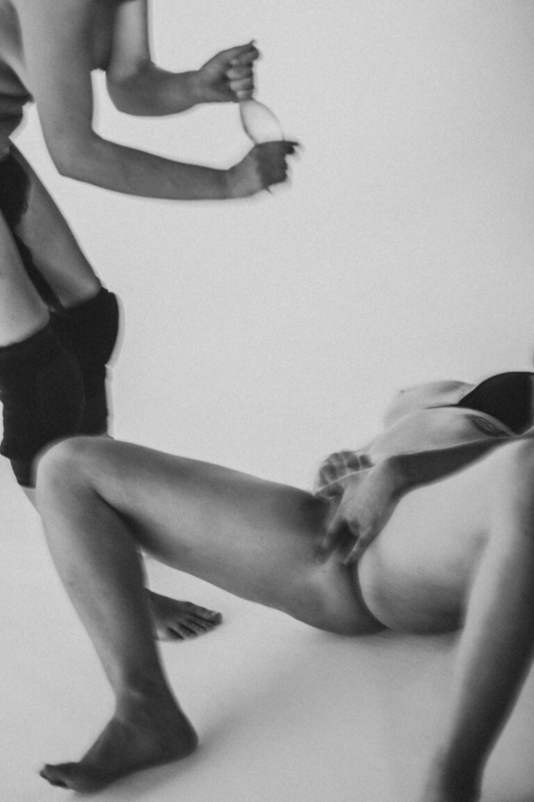 Two naked people in a combative dance pose in black and white with arms intertwined