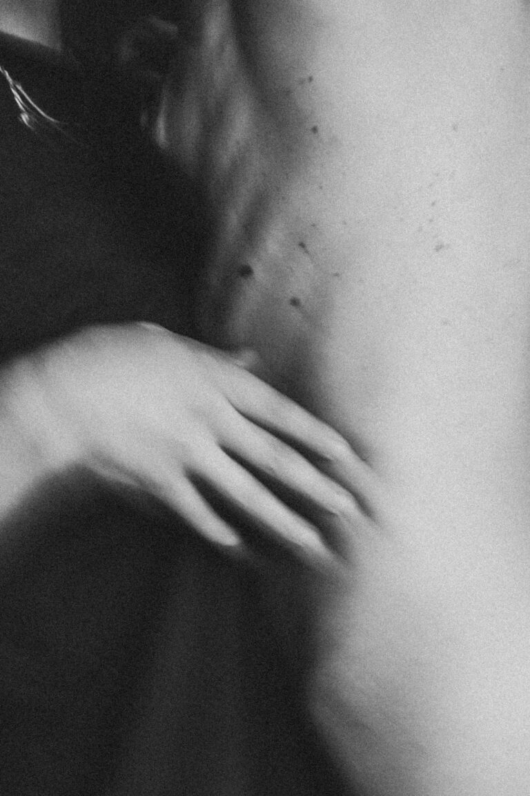 Close-up of naked torso with hand performing an acrobatic movement in black and white