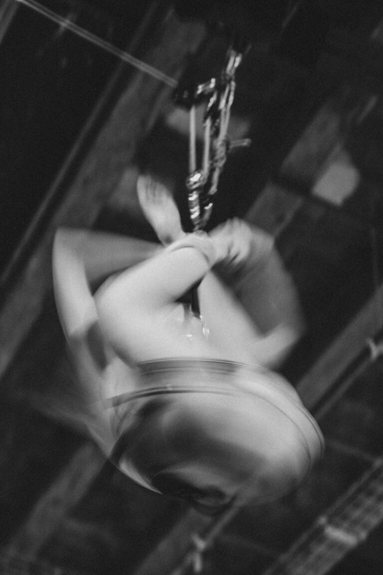 Blurred motion image of naked person performing acrobatic aerial movement in dynamic spinning motion