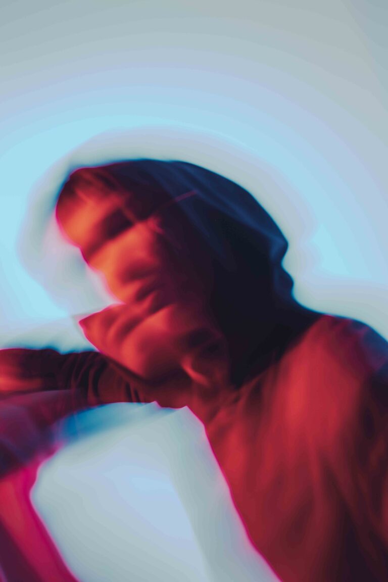 Moving nude figure with bare back in an abstract and colorful aesthetic, captured in vibrant red and blue tones with motion blur.