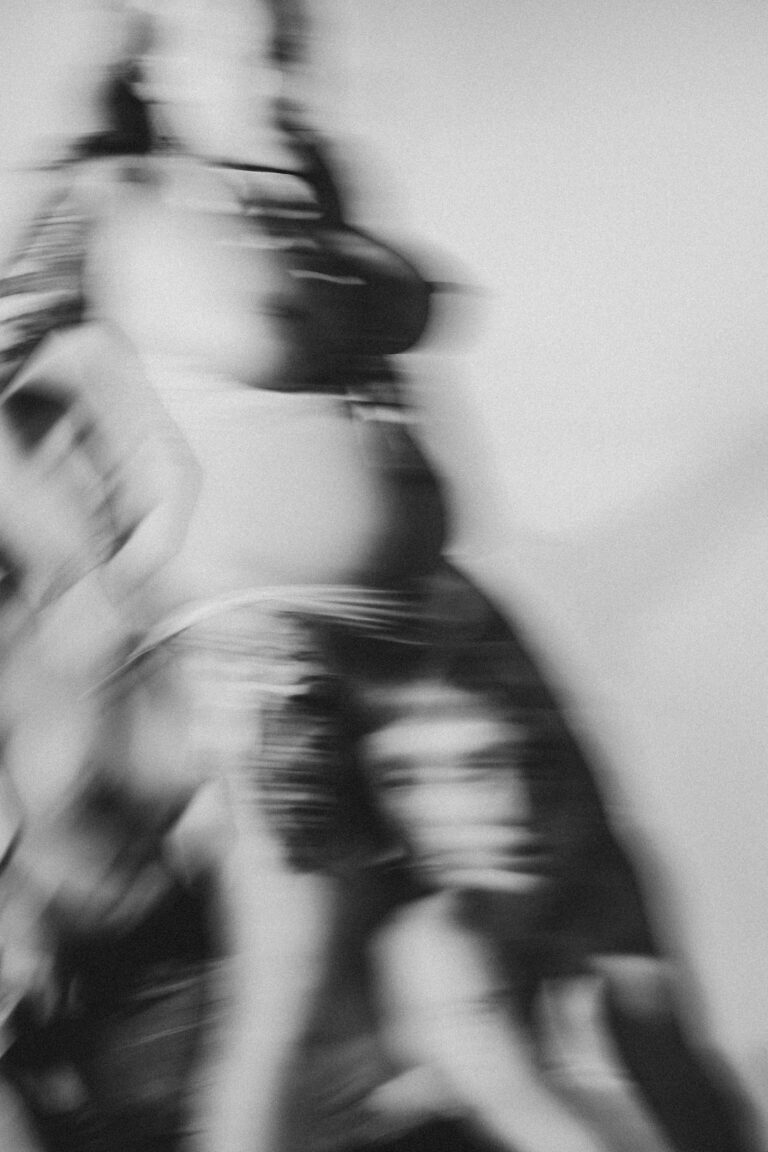 Blurred black and white image of multiple naked people in rapid motion creating abstract shapes