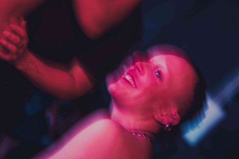 Een groep mensen die zich bezig houden met lichaamswerk of groepsinteractie, met een mix van naakte en geklede individuen die elkaar steun bieden en hun gevoelens delen in een sombere omgeving.