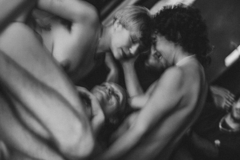 Een groep naakte mensen met Philemon Mukarno die elkaar ondersteunen in een acrobatische houding, met een persoon in het midden die door anderen wordt vastgehouden. De foto is in zwart-wit en geeft een artistieke sfeer weer, met een focus op de menselijke vormen en bewegingen.