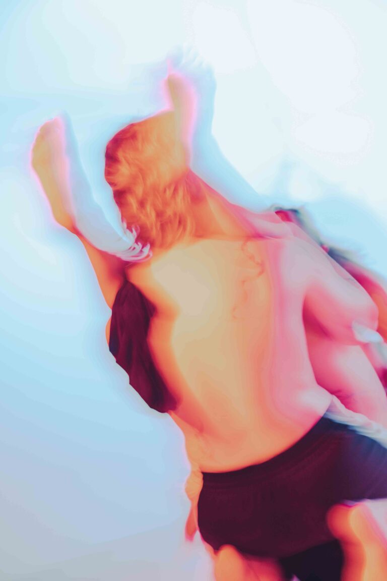 An abstract depiction of a moving nude figure with bare back, captured in vibrant pink, orange and blue tones with dynamic motion blur.