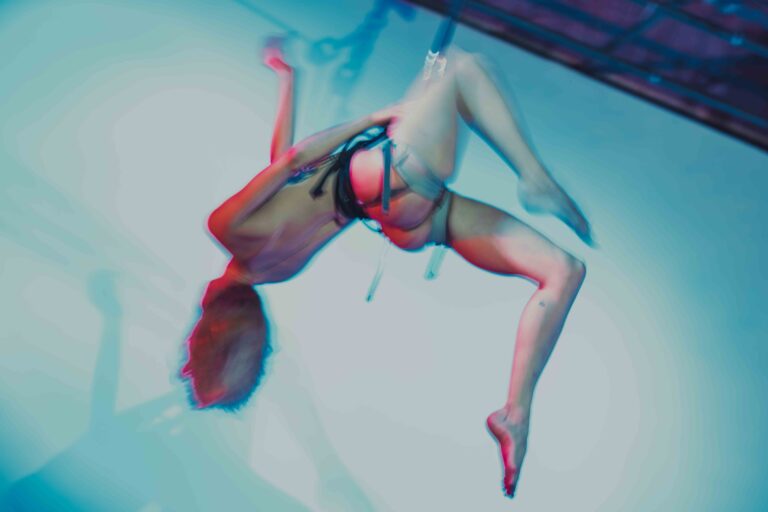 Een figuur hangend in de lucht, met een abstracte en vervaagde uitstraling, gekleed in een harnas en met geen zichtbare kleding, terwijl de achtergrond in zachte kleuren van blauw en roze is.