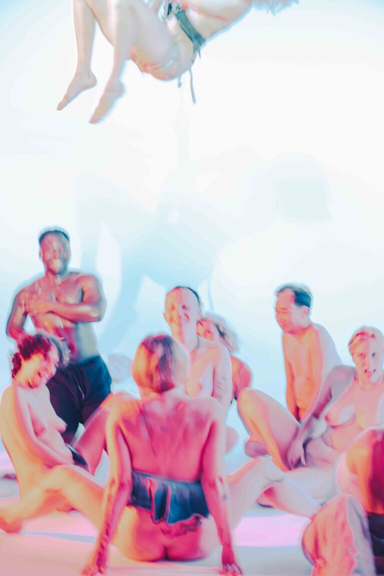 A group of naked people sitting on the ground,