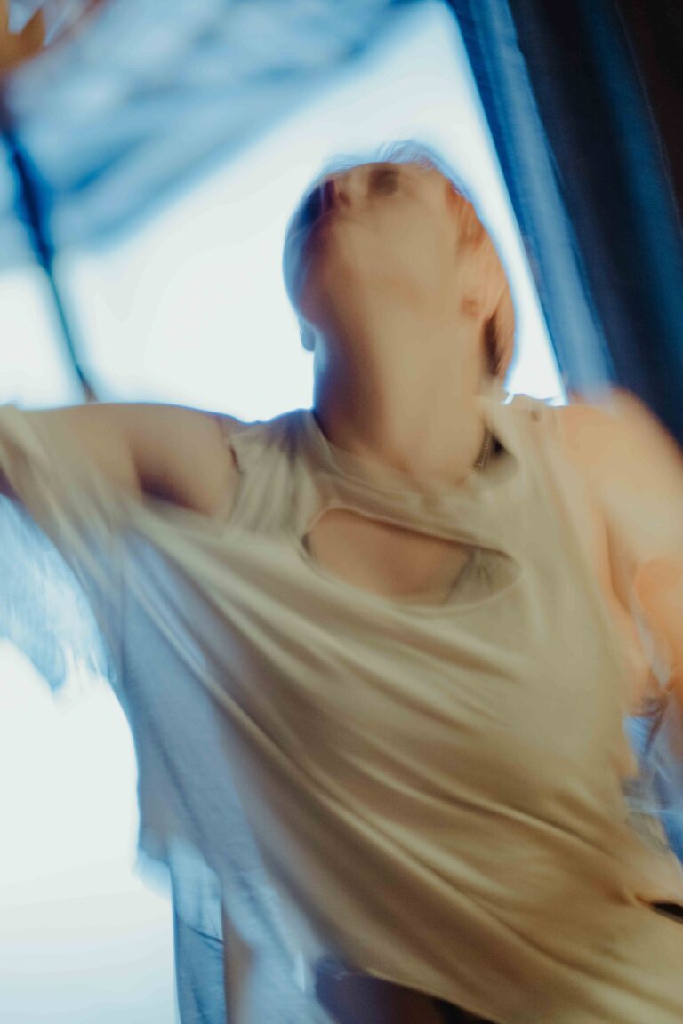 Person with short hair wearing a torn t-shirt in motion blur with blue and white lighting