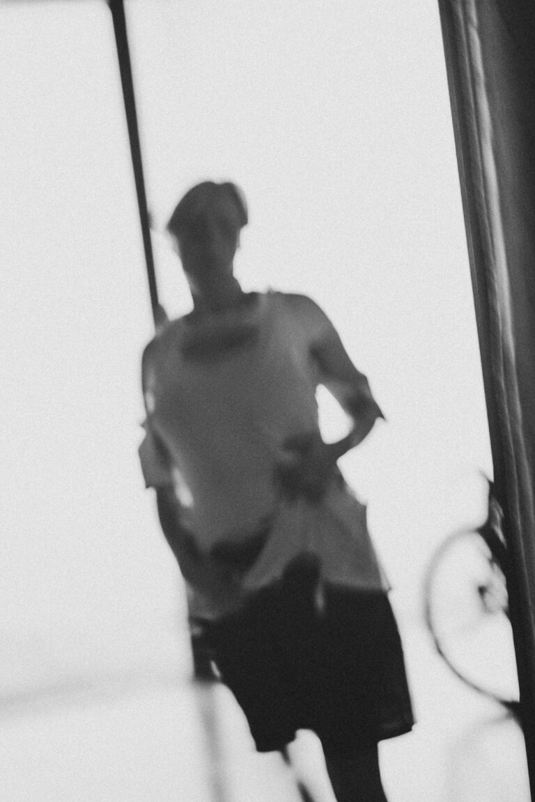 Faded shadow silhouette of a naked person hanging from aerial rope in a performance space