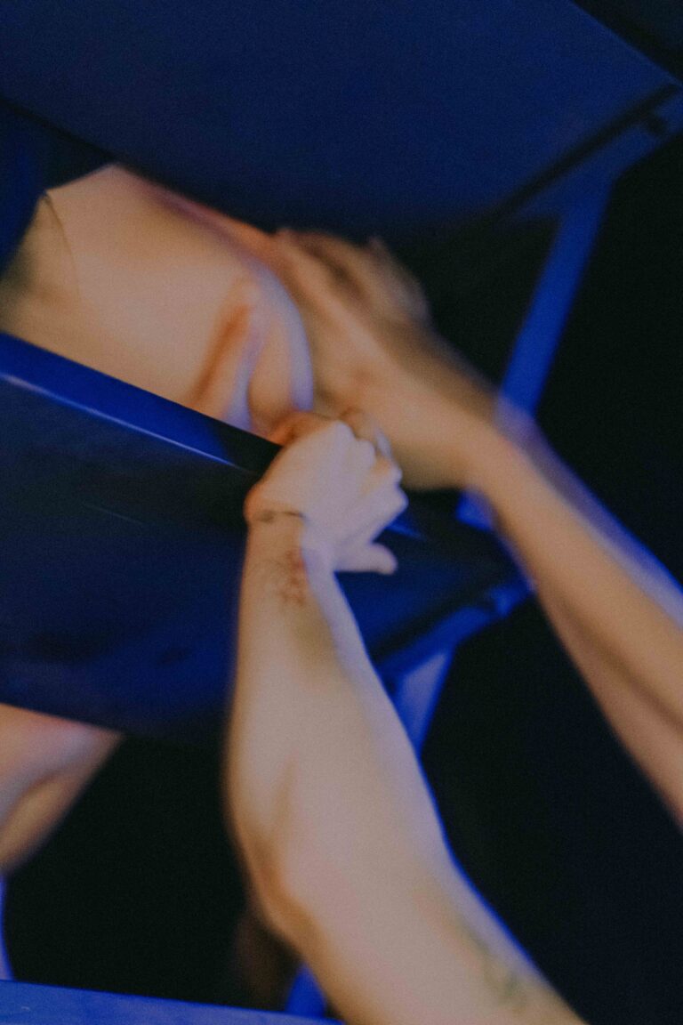 Blurred motion image of nude hands and body in dynamic blue and white lighting