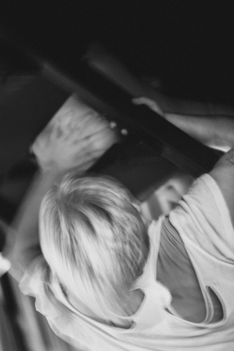 Blurry black and white image of a naked woman with short blonde hair in motion with fabric swirling