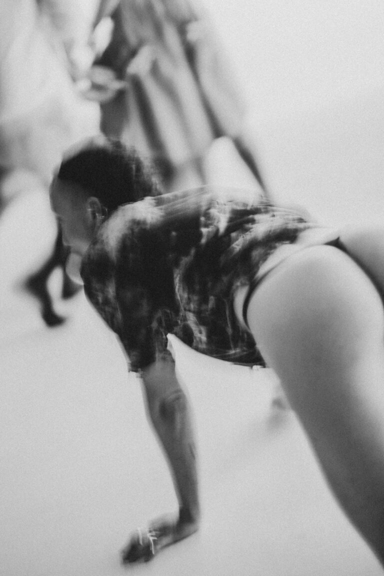 Blurred black and white image of a naked person on hands and knees with arms reaching forward
