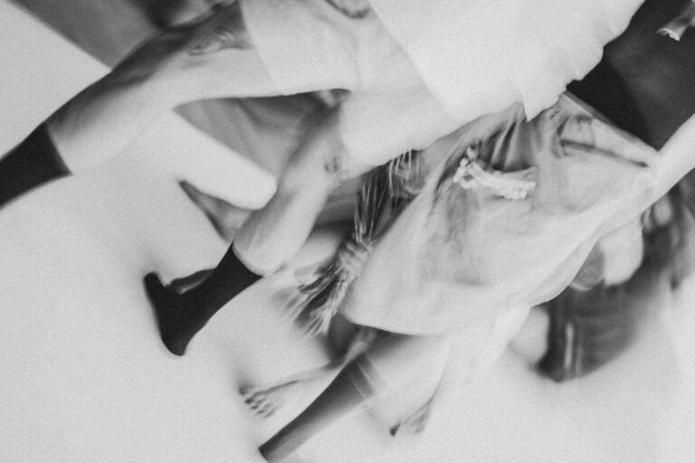 Bewegende blote voeten en benen van verschillende mensen, met enkele benen gekleed in zwarte sokken, op een lichte achtergrond.