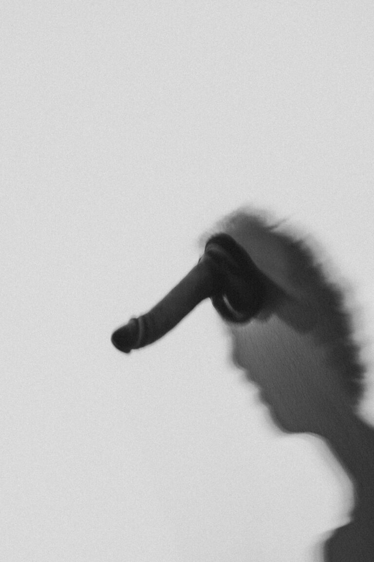 Silhouette of a naked performer in motion with arms extended upward