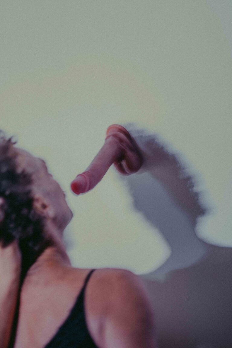 Two women in a blurred motion performance with colorful tones, one topless reaching upward