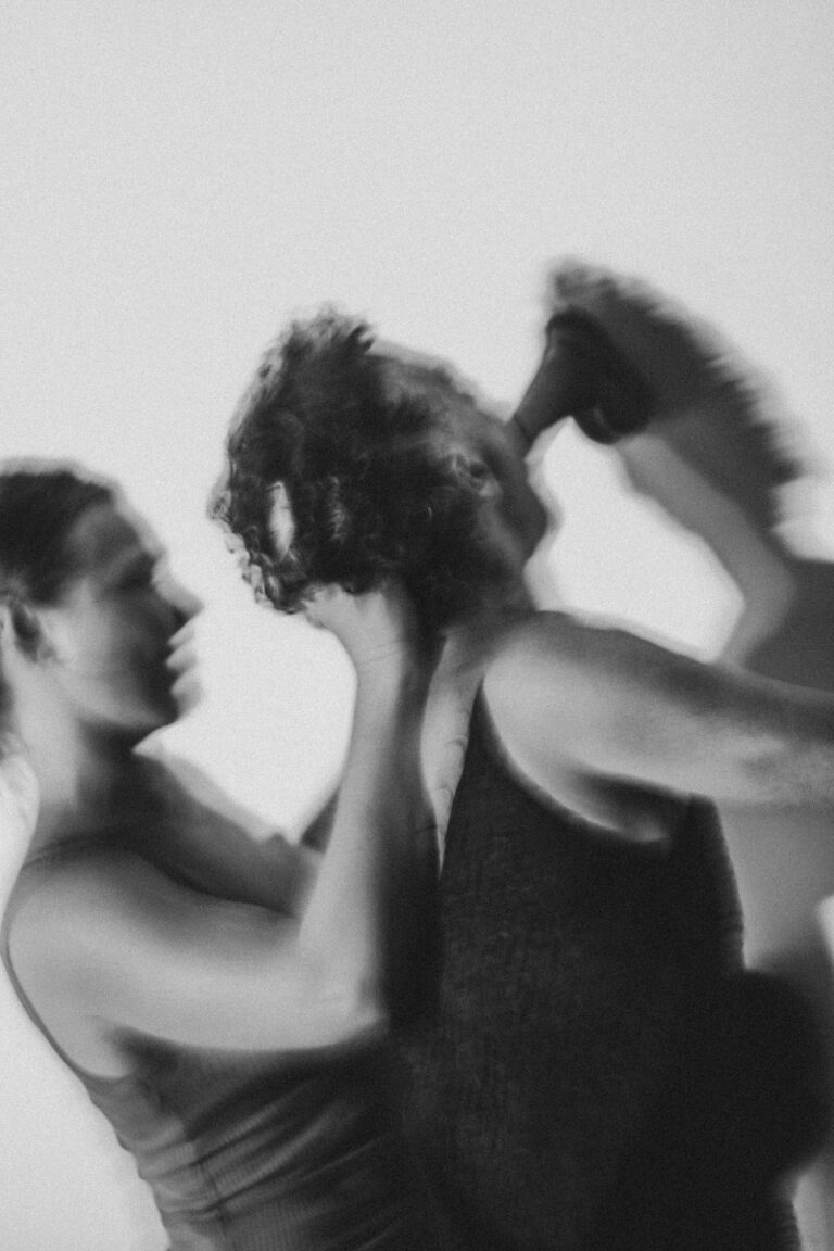 Artistic black and white image of two naked women dancing together with heads touching