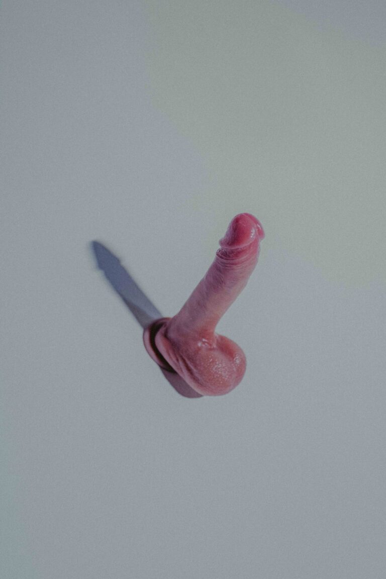 Pink dildo sex toy on a gray background