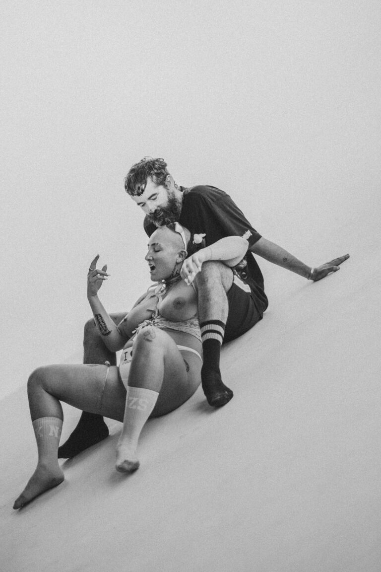 Woman in lingerie and a man with a beard performing an acrobatic dance pose