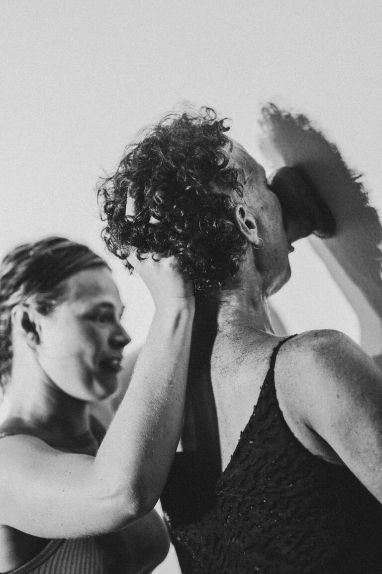 Two women, one with short curly hair and one with hands raised in a dance pose