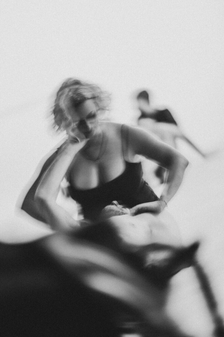 Woman with curly hair in a black top performing an expressive movement