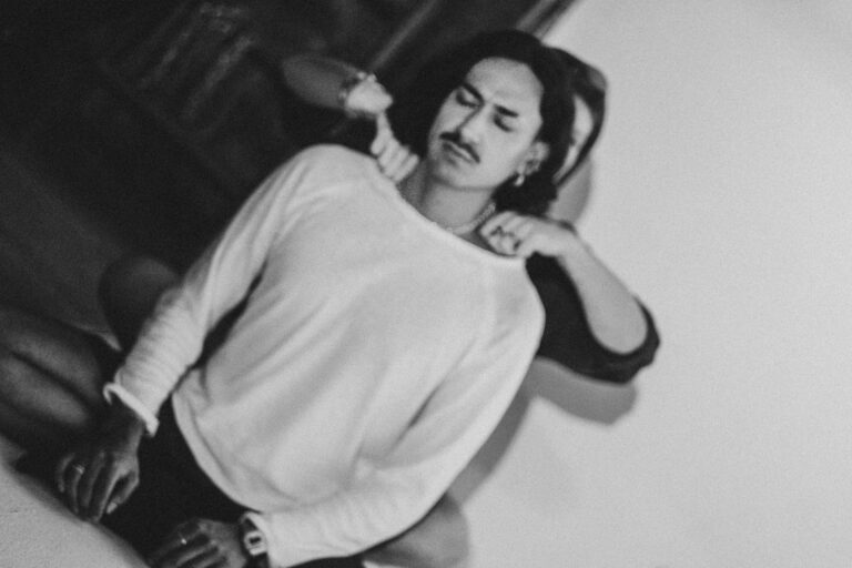 A man with a mustache and long hair in a white